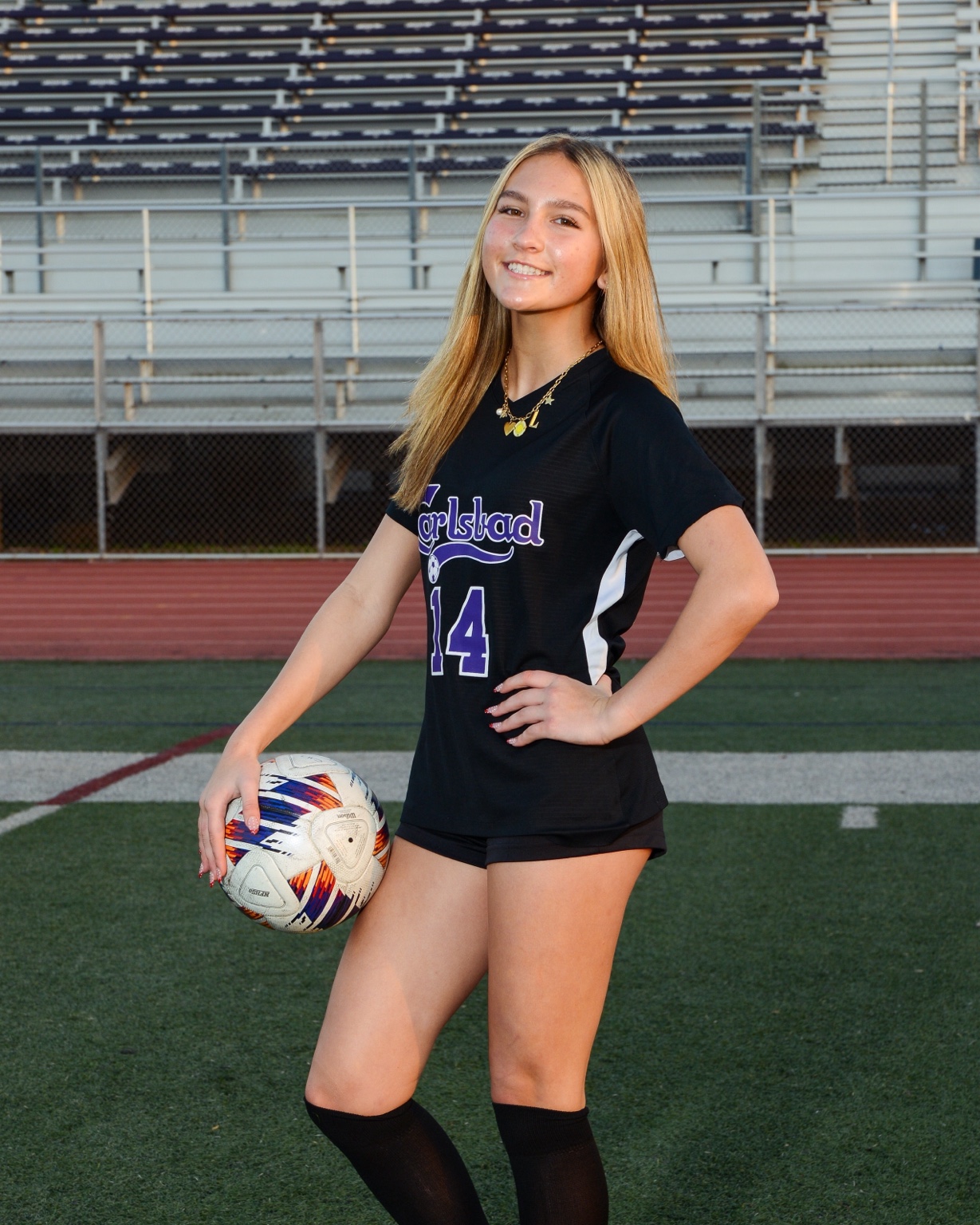 Coach Lilly holding a soccer ball on a soccer field in Carlsbad.